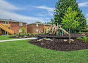 Thumbnail 9 of 14 - A playground with a green slide and a tree in the foreground.