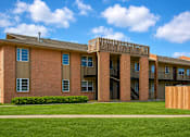 Thumbnail 1 of 3 - A red brick building with a balcony and a green lawn in front.