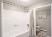 Thumbnail 4 of 18 - A white bathroom with a toilet and a bathtub.
