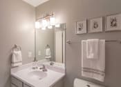 Thumbnail 5 of 18 - A white sink in a bathroom with a mirror and towel rack.