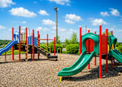 Thumbnail 15 of 18 - A playground with a green slide and a red and blue structure.