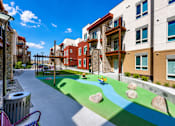 Thumbnail 3 of 25 - A playground with a blue and green surface and rocks.