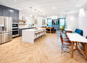 Thumbnail 7 of 25 - A modern kitchen with wooden floors and a dining table with chairs.