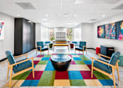 Thumbnail 11 of 25 - A room with a colorful rug and wooden furniture.