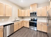 Thumbnail 14 of 25 - A kitchen with wooden cabinets and stainless steel appliances.