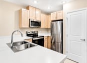 Thumbnail 15 of 25 - A kitchen with a sink, stove, and refrigerator.