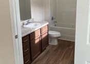 Thumbnail 4 of 6 - A white toilet sits in a bathroom with a white sink and a white bathtub.