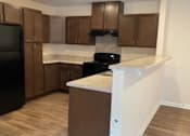 Thumbnail 2 of 6 - A kitchen with brown cabinets and a black refrigerator.