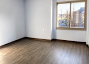Thumbnail 9 of 12 - A room with a window and wooden flooring.