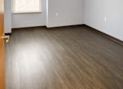 Thumbnail 7 of 12 - A room with a window and wooden flooring.