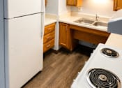 Thumbnail 12 of 12 - A white refrigerator is in a kitchen with wooden cabinets.