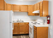 Thumbnail 6 of 12 - A kitchen with wooden cabinets and a white refrigerator.