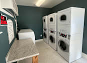 Thumbnail 6 of 9 - a laundry room with four washes and a table with a bench