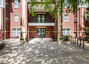 Thumbnail 2 of 13 - A red brick building with a courtyard in front.