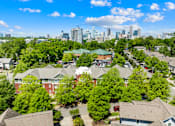 Thumbnail 9 of 13 - A suburban neighborhood with houses and trees in the foreground and a city skyline in the background.