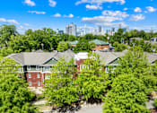 Thumbnail 8 of 13 - A view of a residential area with houses and trees in the foreground and a city skyline in the background.