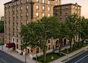 Thumbnail 8 of 16 - A large building with a flag on top is surrounded by trees.