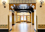 Thumbnail 14 of 16 - A hallway with a patterned floor and a chandelier hanging from the ceiling.