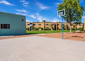 Thumbnail 3 of 14 - A basketball court with a hoop and a building in the background.
