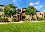 Thumbnail 2 of 14 - A building with a green lawn in front and trees around it.