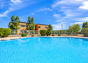 Thumbnail 6 of 14 - A swimming pool in front of a building with a fence around it.