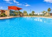 Thumbnail 7 of 14 - A large swimming pool with a red umbrella.