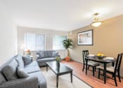Thumbnail 11 of 15 - A living room with a grey couch, a black coffee table, and a dining table set for two.