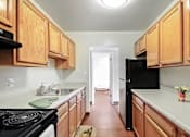Thumbnail 5 of 15 - A kitchen with wooden cabinets and a black refrigerator.