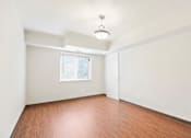 Thumbnail 12 of 15 - Empty room with wooden floor and white walls.