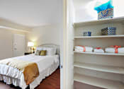 Thumbnail 14 of 15 - A bedroom with a bed and a closet with shelves.