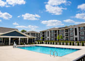 Thumbnail 15 of 22 - A swimming pool in front of a building with a black fence.