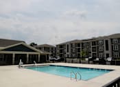 Thumbnail 15 of 22 - A swimming pool in front of a building with a black fence.