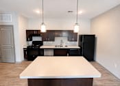 Thumbnail 16 of 22 - A kitchen with a black refrigerator and a white island.