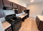 Thumbnail 14 of 22 - A kitchen with a black stove top oven and wooden cabinets.