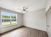 Thumbnail 22 of 22 - A room with a ceiling fan and a window overlooking a parking lot.