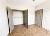 Thumbnail 18 of 22 - A room with a wooden floor and two doors, one of which is open.