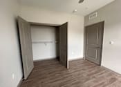 Thumbnail 18 of 22 - A room with a wooden floor and two open doors.