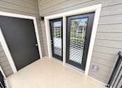 Thumbnail 10 of 22 - A black door is on the left and a window with blinds is on the right.