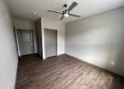 Thumbnail 21 of 22 - A room with a ceiling fan and wooden flooring.