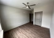Thumbnail 17 of 22 - A room with a ceiling fan and wooden flooring.