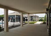 Thumbnail 2 of 22 - A long covered walkway with pillars on either side.