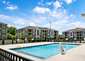 Thumbnail 3 of 22 - A swimming pool in front of apartment buildings.