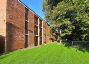 Thumbnail 7 of 7 - a large brick building with a grass yard and trees