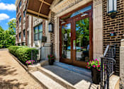Thumbnail 1 of 43 - A building with a brown door and windows with a hedge in front.