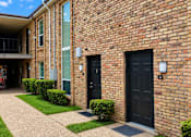 Thumbnail 3 of 10 - A brick building with a balcony and black doors.