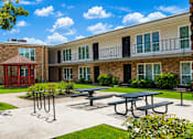 Thumbnail 2 of 10 - A sunny day at the courtyard of a brick building with a red entrance and a gazebo.