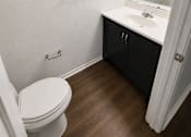 Thumbnail 22 of 23 - A white toilet sits in a bathroom with a sink and mirror.