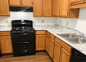 Thumbnail 13 of 23 - A black stove in a kitchen with wooden cabinets.