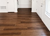 Thumbnail 16 of 23 - A room with white walls and a brown floor.