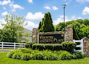 Thumbnail 4 of 23 - A sign for Country Apartments Place is surrounded by greenery.